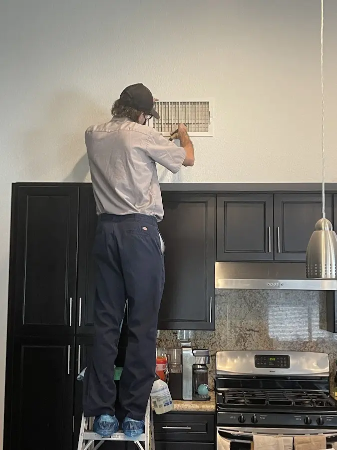 Technician inspecting an air vent during HVAC service in Stafford